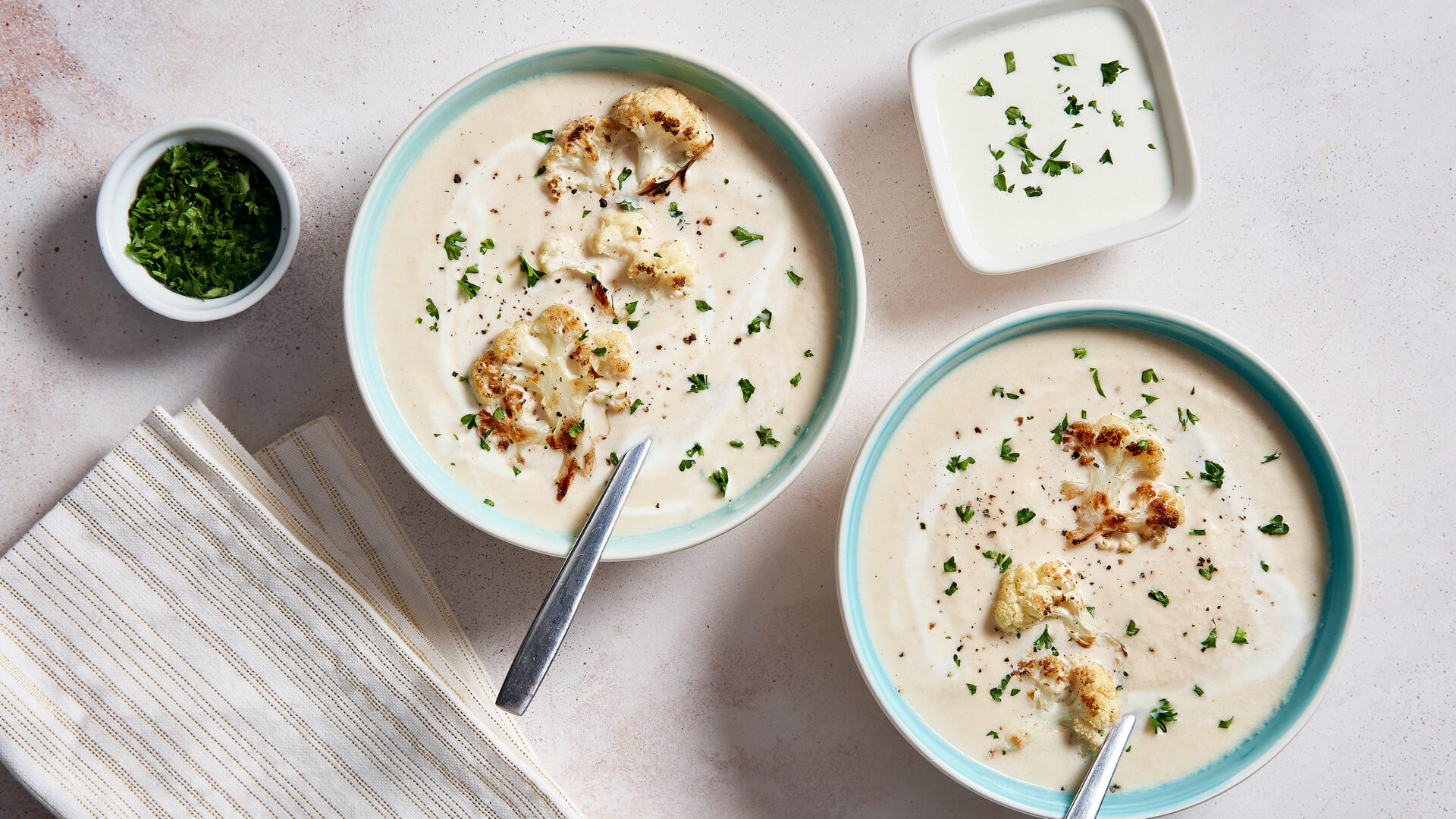  Two bowls of cauliflower soup sprinkled with chopped parsley 