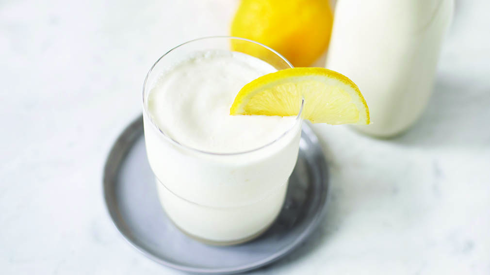 A glass of whipped lemonade topped with a wedge of lemon.