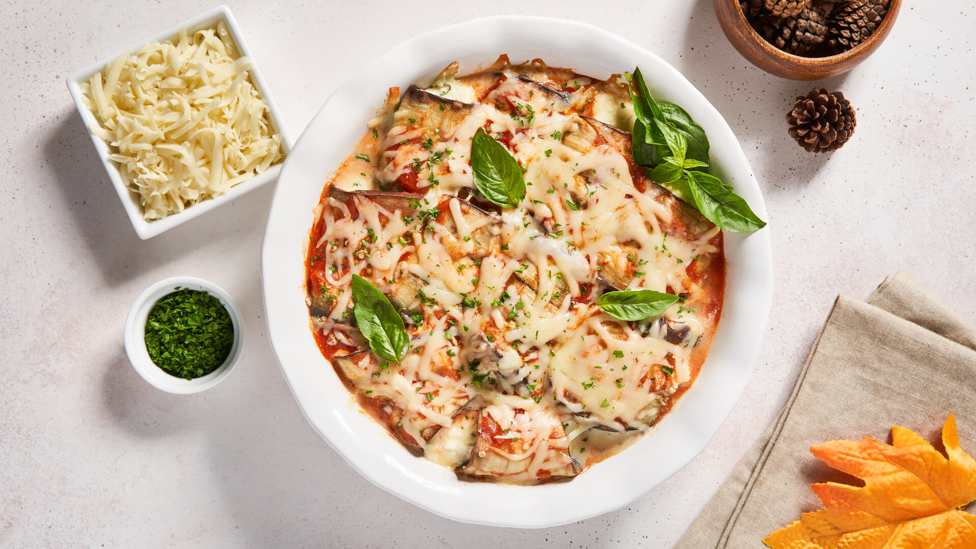 Casserole dish with eggplant, cheese and tomato sauce served with shredded cheddar and herbs