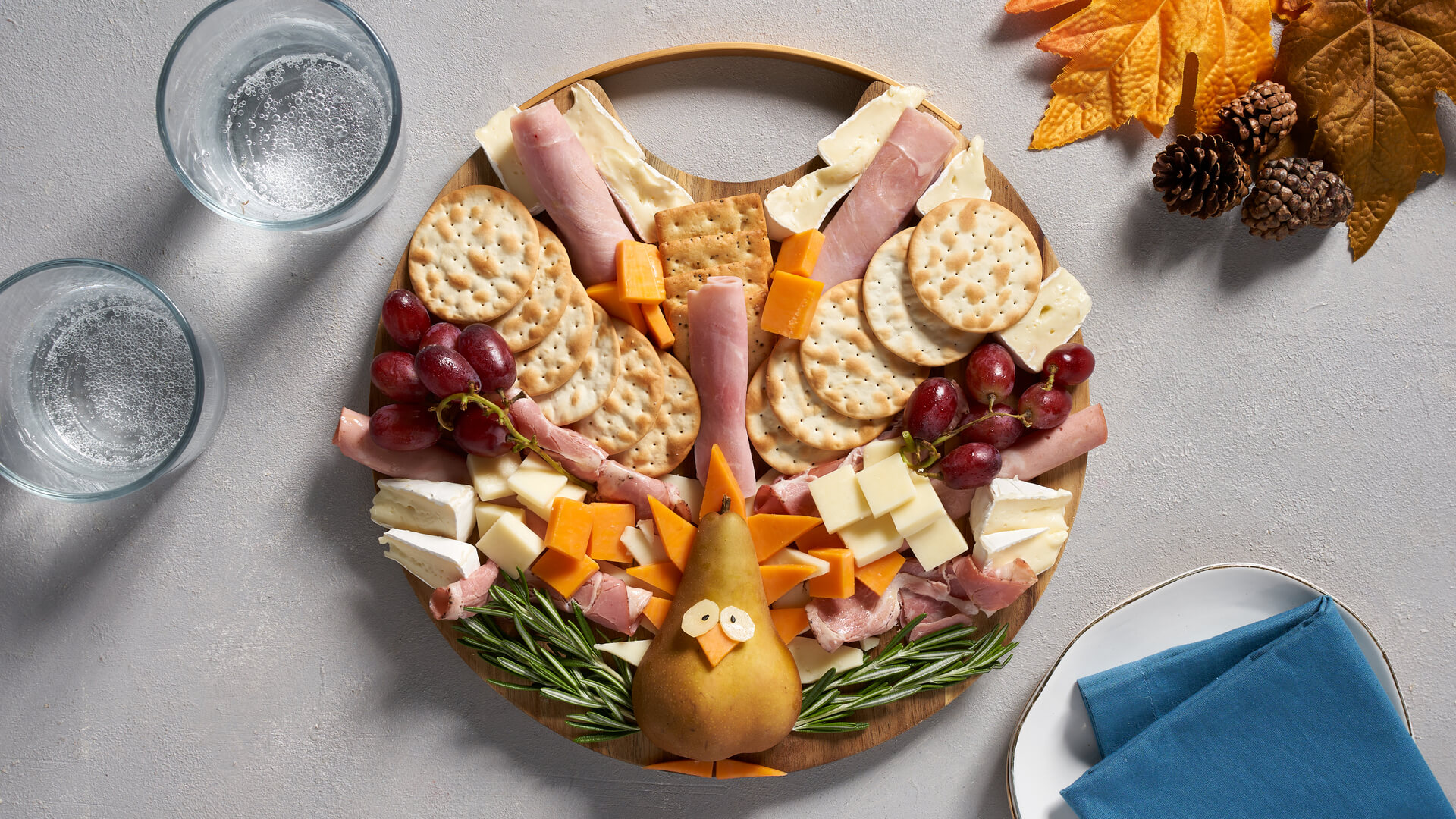 A turkey-shaped snack board with cheese as feathers, pears as the base and crackers and meat to accompany